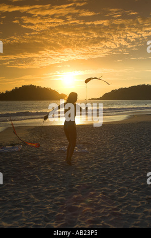 Jeune femme maillot de twirling poi rubans dans coucher du soleil plage de Palolem sud de Goa Inde Banque D'Images