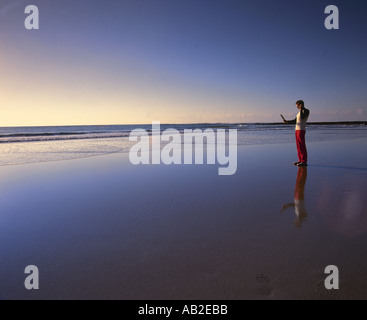 Man with mobile phone on an empty beach dans la soirée Banque D'Images