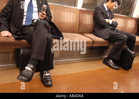 Les banlieusards, deux hommes assis sur un train de métro de Tokyo au Japon Banque D'Images