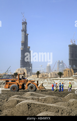 Petit groupe d'hommes travaillant dans la construction site avec Burj Dubai tower en arrière-plan, Dubaï Banque D'Images