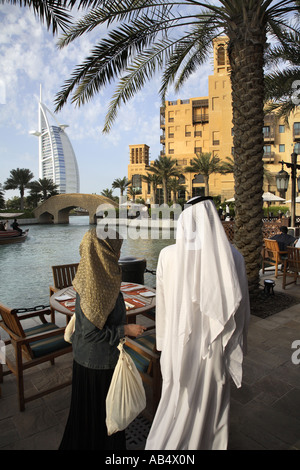 Couple arabe en costume traditionnel marche dans la Madinat Jumeirah avec hôtel Burj al Arab de Dubaï, en arrière-plan Banque D'Images
