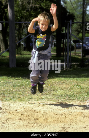 6 ans saute dans un tas de sable dans le cadre d'un jour de jeu de l'école élémentaire Banque D'Images