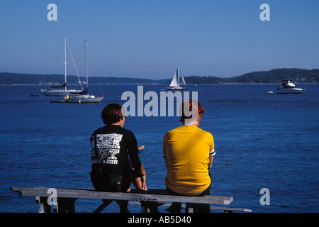 Couple est assis sur une table de pique-nique sur le Port Townsend WA waterfront looking out à l'inlet de l'Amirauté à l'île de Whidbey à distance Banque D'Images