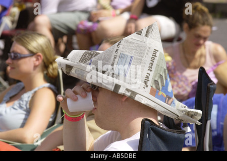 Public visé en plein soleil, un journal portant hat, à l'écoute de bande au Festival de jazz annuel Brecon Powys Pays de Galles UK Banque D'Images