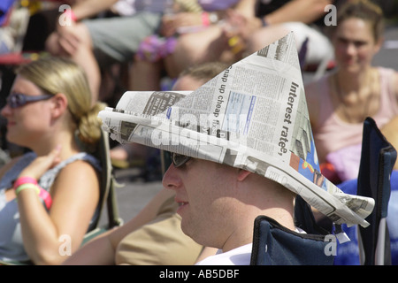 Public visé en plein soleil, un journal portant hat, à l'écoute de bande au Festival de jazz annuel Brecon Powys Pays de Galles UK Banque D'Images