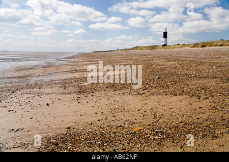 Rejeter Head Lighthouse à distance avec plage en premier plan dans un ciel ensoleillé nuageux jour lumineux Banque D'Images