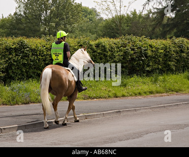 Cavalier et son cheval femelle portant sur route s'il vous plaît laissez-passer lentement l'échelle de signer sur veste fluorescente Wales UK Banque D'Images