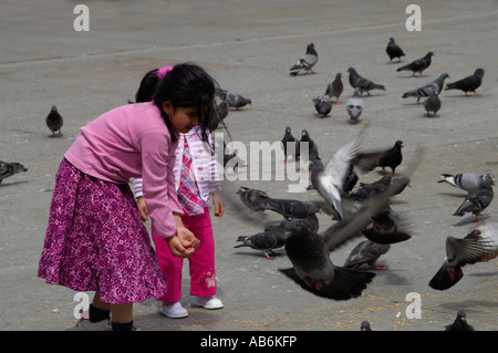 Les enfants l'alimentation des pigeons à Trafalgar Square Londres Angleterre Banque D'Images