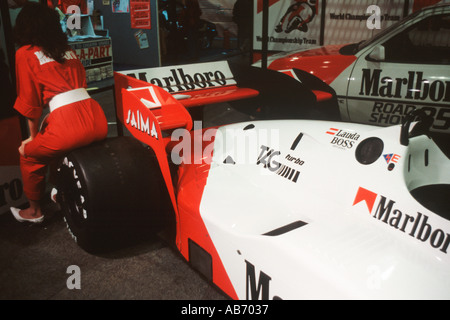 TAG McLaren F1 location de Niki Lauda sur un stand salon de l'automobile au milieu des années 1980 avec soutien publicité girl perché sur l'un des pneus arrière Banque D'Images