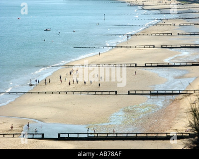 Vue aérienne sur la côte avec des gens sur une plage de vacances sablonneuse à marée basse et des brise-lames à Sandown Isle of Wight, Angleterre, Royaume-Uni Banque D'Images