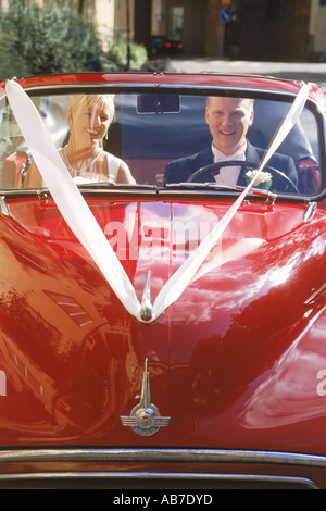 Le couple mariage rouge vif en voiture classique Banque D'Images