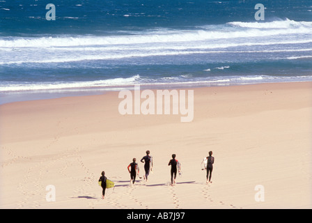 Surfers exécuter dans le sable de Guincho la célèbre plage de surf près de Lisbonne Portugal Banque D'Images
