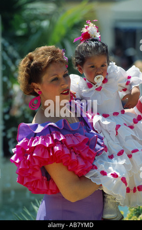 Mother holding daughter sur les armes, en tenue de fête, Andalousie, Espagne Banque D'Images
