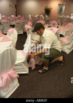 Jeune homme attachant arcs sur des chaises couverts Rose Banque D'Images