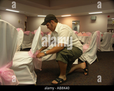 Jeune homme attachant arcs sur des chaises couverts Rose Banque D'Images