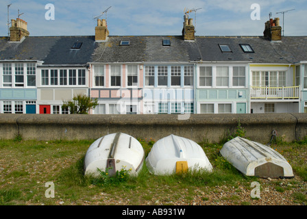 Front cottages avec terrasse tournée vers le blanc trois barques et mur de la mer au premier plan, Whitstable, Kent, Angleterre. Banque D'Images