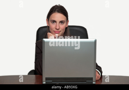 Young businesswoman sitting at desk in office in front of laptop computer smiling portrait Banque D'Images