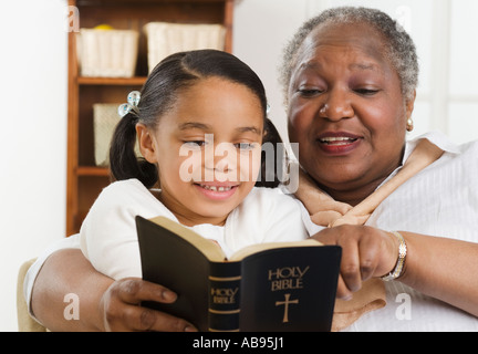 Senior woman lire la Bible à sa petite-fille Banque D'Images