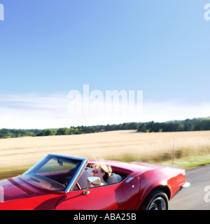 Blonde girl driving red corvette convertible Banque D'Images