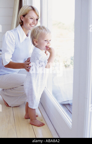 Tout-petit et maman regarder par la fenêtre Banque D'Images