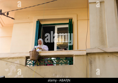 Femme transportant jusqu'épicerie dans son appartement avec un panier, Scènederue, Alexandria, Egypte Banque D'Images