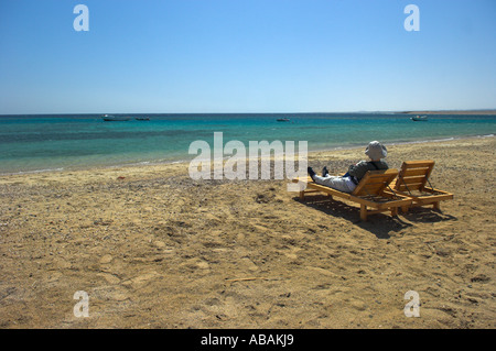 Des chaises longues inclinables sur Tondoba beach Mer Rouge Egypte avec Femme au chapeau de soleil et vêtements de protection Banque D'Images