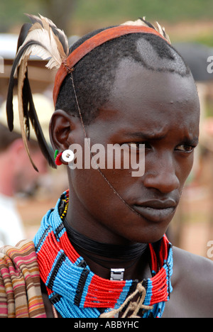 Portrait jeune homme du peuple Banna avec des plumes sur la tête et collier coloré sur le marché de l'Éthiopie Keyafer Banque D'Images