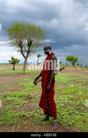 De l'homme les Mursi personnes portant une cape rouge et une Kalaschnikow se réveille dans le paysage de l'Ethiopie Banque D'Images