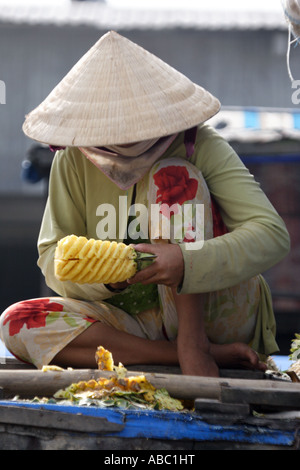 Une femme coupe ananas en un style sucette forme au marché flottant de Cai Rang dans le Delta du Mekong, Vietnam. Banque D'Images