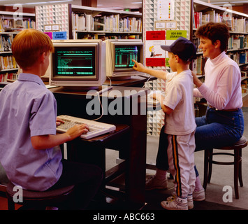 - Les terminaux d'ordinateur dans la section pour enfants de la bibliothèque ; les enfants et la mère travaillant à l'ordinateur / USA. Banque D'Images
