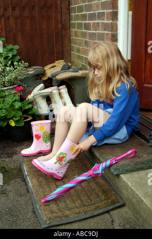 Girl putting sur bottes Wellington pour stockage Jardin wellies Banque D'Images