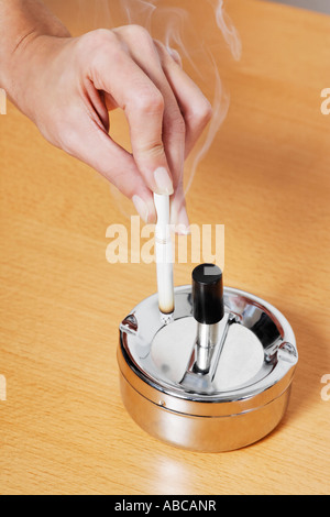 Une cigarette à l'écrasement des mains un cendrier sur une table Banque D'Images