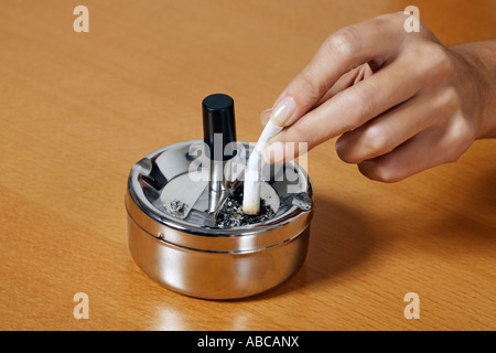 Une cigarette à l'écrasement des mains un cendrier sur une table Banque D'Images