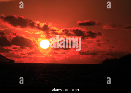 Vue depuis un bateau voile d'un coucher de soleil sur la baie Sainte Anne à Praslin Seychelles, océan Indien Banque D'Images