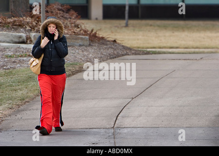 Une femme utilise un téléphone cellulaire pendant qu'ils marchaient sur le campus de l'Université du Nebraska à Lincoln, Nebraska. Banque D'Images