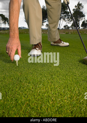 Man placing balle de golf sur tee Banque D'Images