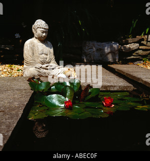 Une statue de Bouddha à côté d'un étang, et encore une lis Banque D'Images