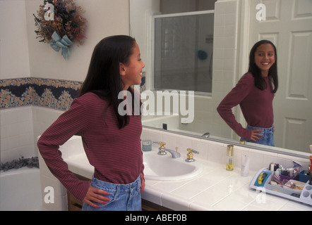 Fille d'interpolations entre 11-13 ans admiring Herself en miroir de salle de réflexion - mixte. Banque D'Images