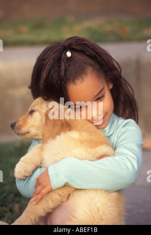 La diversité raciale entre multi raciales diversifiées interracial multiculturelles 5 enfant de 7 ans tient biracial pup close up front view © Myrleen Pearson Banque D'Images