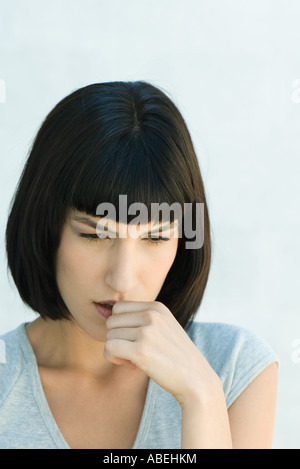 Woman biting pouce et regardant vers le bas, la tête et épaules, portrait
