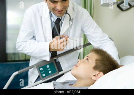 Doctor talking with boy lying in hospital bed Banque D'Images