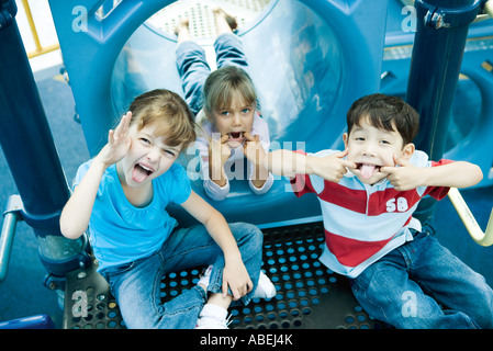 Les enfants à l'équipement de jeu, faisant des grimaces à l'appareil photo Banque D'Images