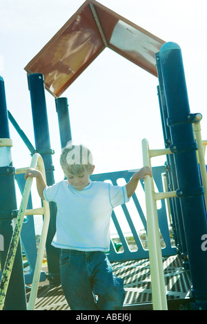 Garçon sur l'équipement de terrain, la maintenant sur rambarde Banque D'Images