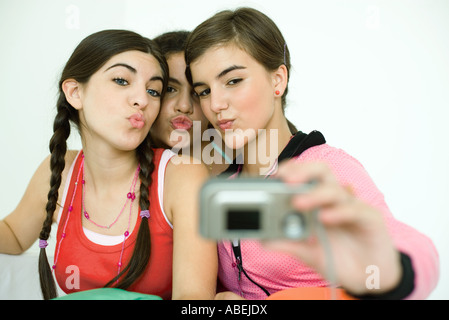 Trois jeunes amis féminins gauchissement comme on prend des photos avec un appareil photo numérique Banque D'Images