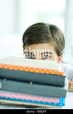 Teen girl looking at camera sur pile de livres Banque D'Images