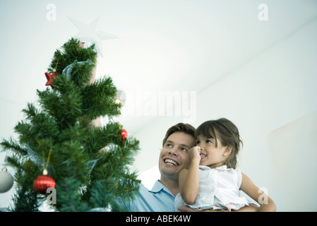 Père et fille plaçant star en haut de l'arbre de Noël Banque D'Images