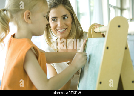 Mère et fille ensemble en tant que fille attire l'on chalkboard Banque D'Images