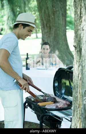 Man grilling meat sur barbecue Banque D'Images