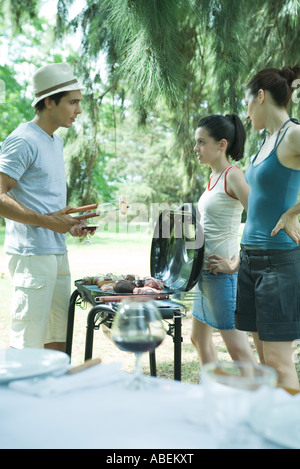 Griller la viande sur un barbecue en famille Banque D'Images