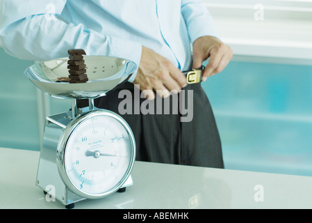 Homme debout par l'échelle contenant des morceaux de chocolat sur l'échelle de cuisine Banque D'Images